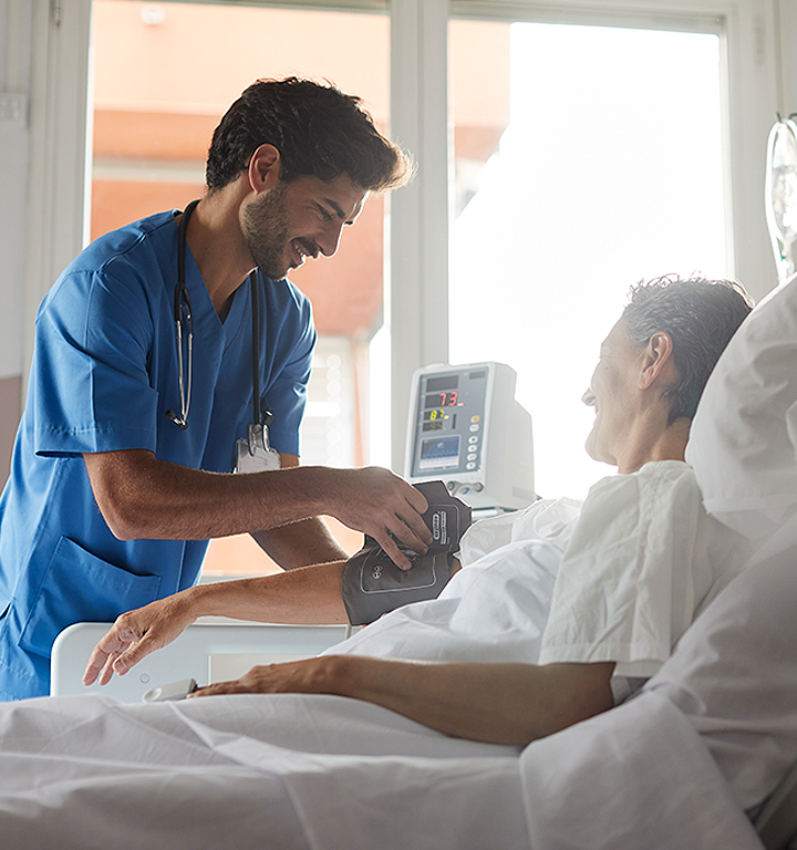Nurse wearing scrubs and stethoscope, smiling at the camera.
