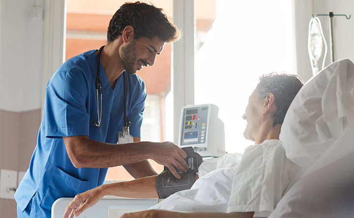Nurse wearing scrubs and stethoscope, smiling at the camera.